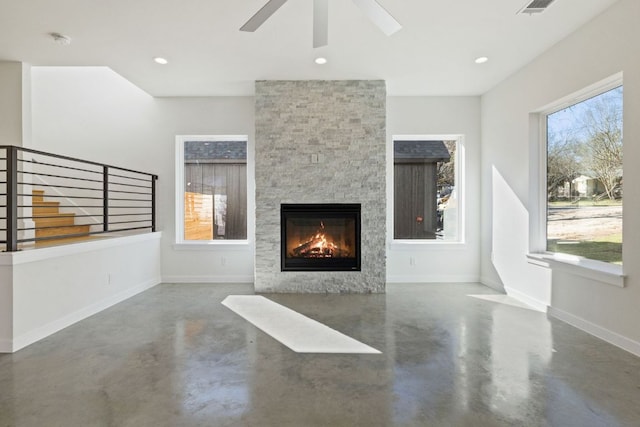 unfurnished living room featuring finished concrete flooring, baseboards, stairway, a stone fireplace, and recessed lighting