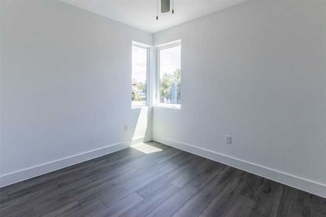 unfurnished room featuring dark wood-style flooring, ceiling fan, and baseboards