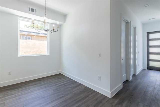 unfurnished dining area featuring dark wood-type flooring, a chandelier, visible vents, and baseboards