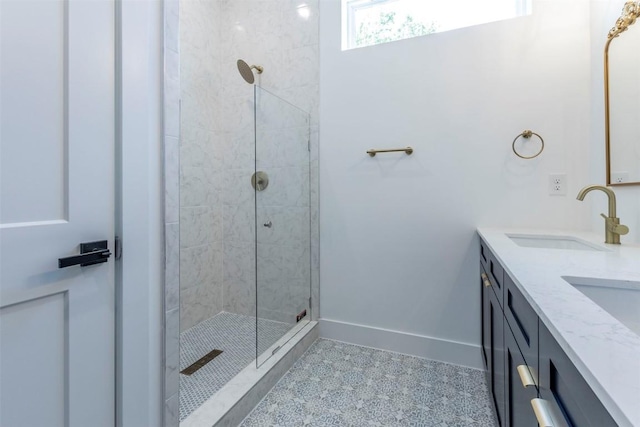 bathroom with double vanity, baseboards, tile patterned flooring, a tile shower, and a sink