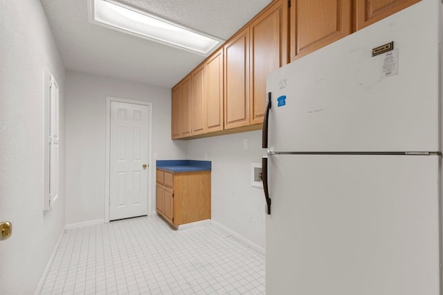 kitchen featuring freestanding refrigerator and baseboards