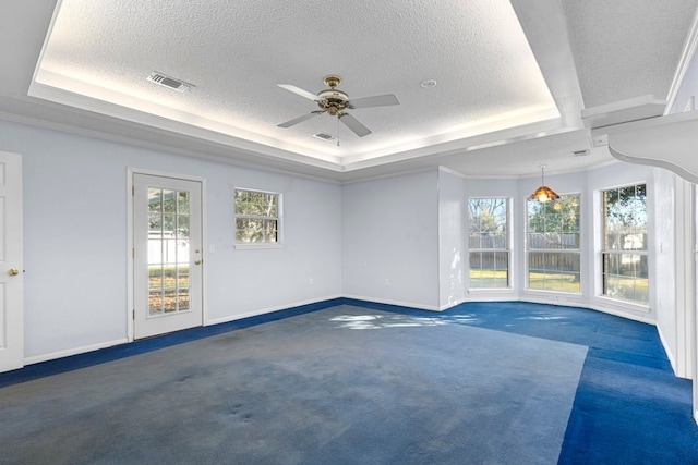 unfurnished room featuring a textured ceiling, visible vents, baseboards, dark colored carpet, and a raised ceiling