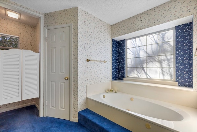 full bath with a closet, a garden tub, a textured ceiling, and wallpapered walls