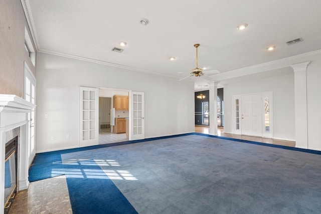 unfurnished living room with carpet floors, visible vents, ornamental molding, french doors, and a glass covered fireplace