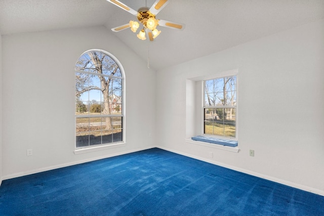 spare room with lofted ceiling, a ceiling fan, dark colored carpet, and a wealth of natural light