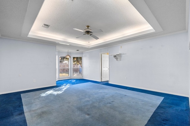 unfurnished room featuring a textured ceiling, carpet flooring, visible vents, baseboards, and a raised ceiling