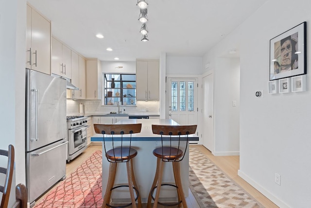 kitchen featuring a center island, tasteful backsplash, a sink, high quality appliances, and a kitchen bar