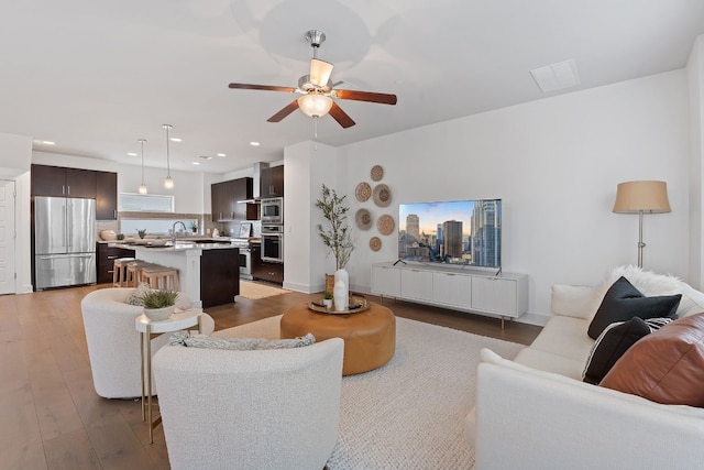 living area with wood-type flooring, baseboards, a ceiling fan, and recessed lighting