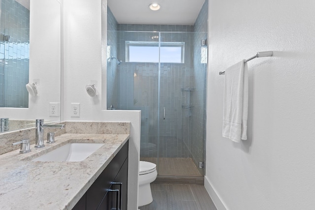 bathroom featuring a stall shower, vanity, toilet, and baseboards