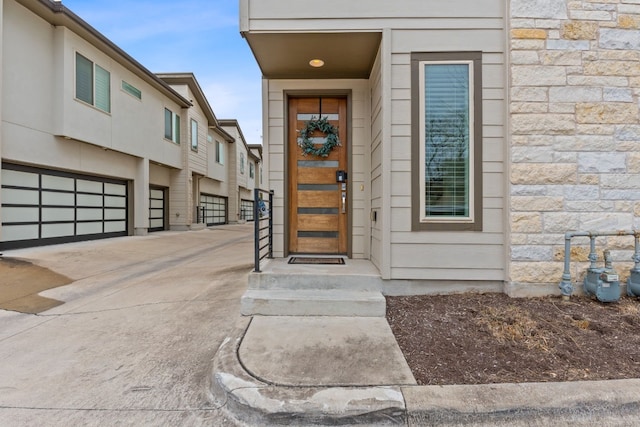 view of exterior entry with stone siding and driveway