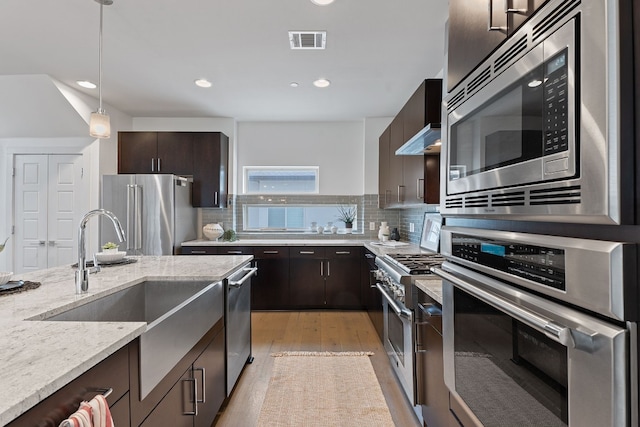 kitchen featuring visible vents, light wood finished floors, dark brown cabinets, and high quality appliances