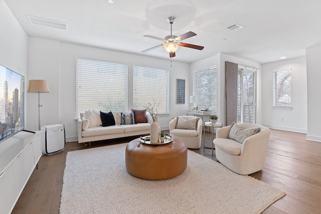 living room featuring wood-type flooring, visible vents, and baseboards