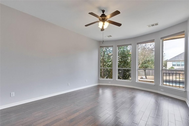 unfurnished room featuring dark wood-type flooring, visible vents, and baseboards