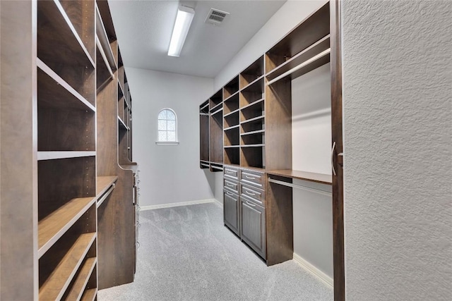 walk in closet with visible vents, carpet flooring, and built in study area