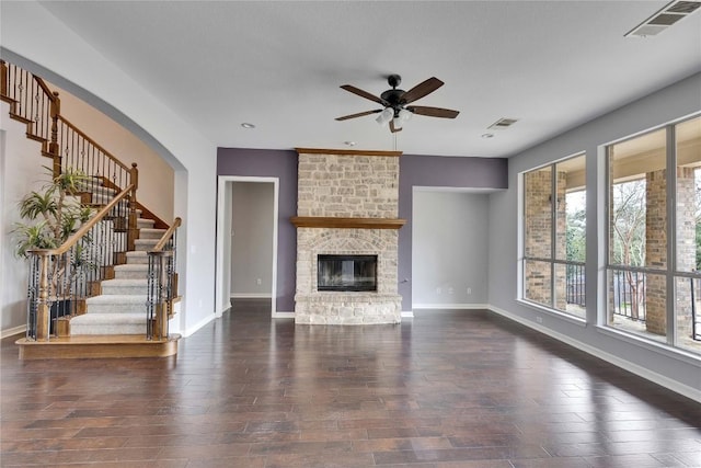 unfurnished living room featuring a fireplace, visible vents, ceiling fan, wood finished floors, and baseboards