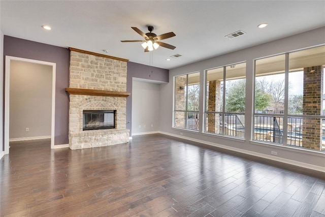 unfurnished living room featuring a large fireplace, plenty of natural light, visible vents, and dark wood-type flooring