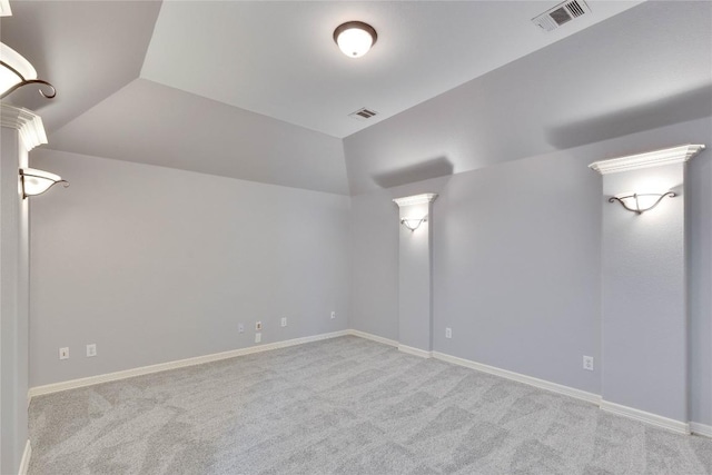 empty room featuring carpet, visible vents, vaulted ceiling, and baseboards