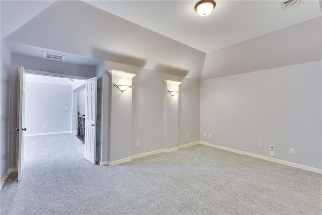 carpeted spare room featuring baseboards, visible vents, and vaulted ceiling