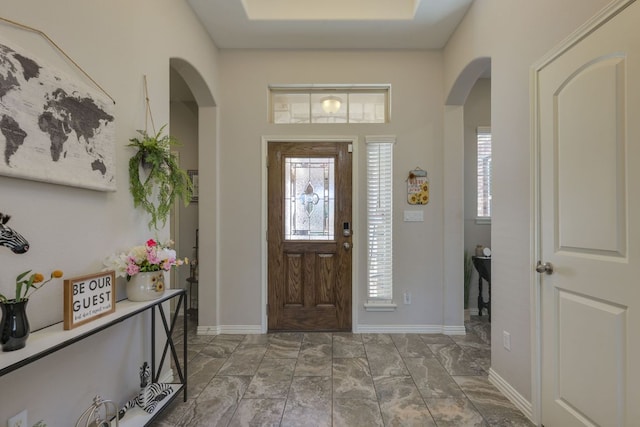 entrance foyer with a healthy amount of sunlight, baseboards, and arched walkways