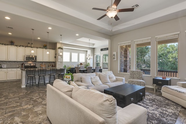 living area with a tray ceiling, a ceiling fan, visible vents, and recessed lighting