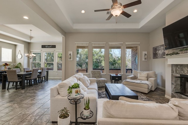 living area with baseboards, plenty of natural light, a tray ceiling, and a tiled fireplace