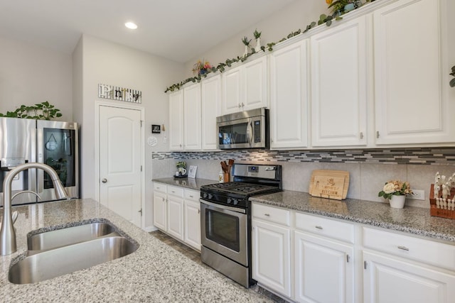 kitchen featuring white cabinets, backsplash, stainless steel appliances, and a sink