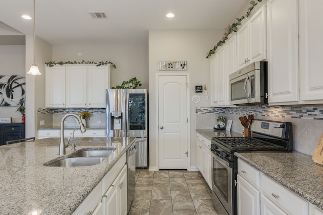 kitchen featuring visible vents, white cabinets, light stone counters, appliances with stainless steel finishes, and a sink