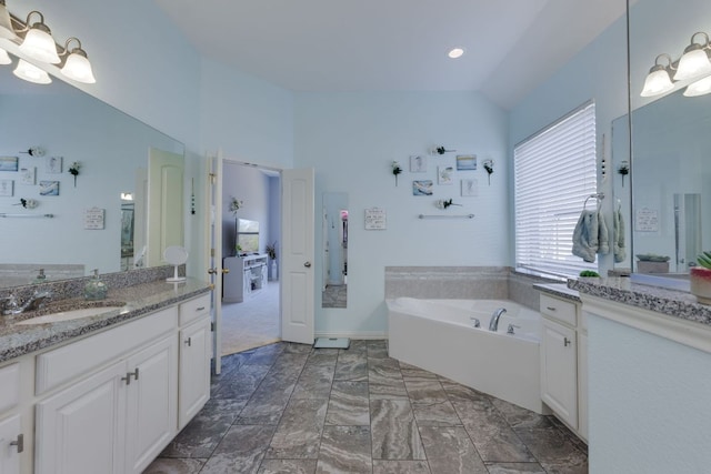 bathroom featuring vaulted ceiling, two vanities, a sink, and a bath