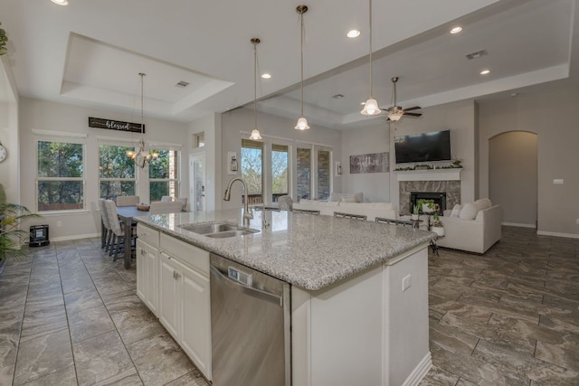 kitchen with a sink, visible vents, a tray ceiling, and dishwasher