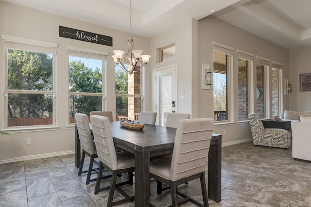 dining space with a chandelier, a wealth of natural light, a tray ceiling, and baseboards