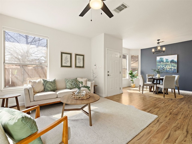 living area featuring a healthy amount of sunlight, light wood-style flooring, visible vents, and baseboards