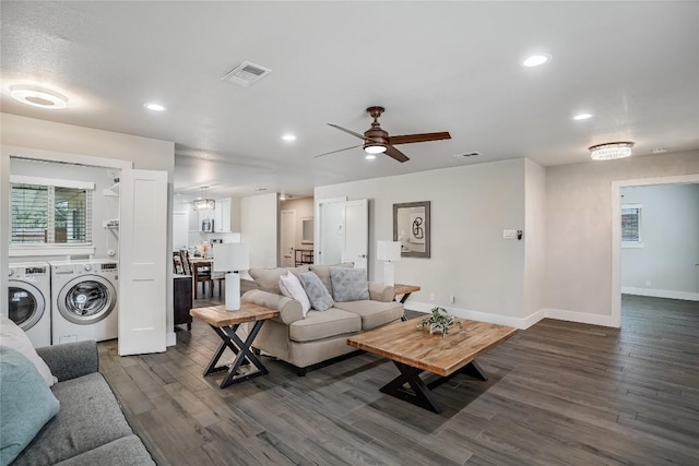 living area with washer and dryer, visible vents, dark wood finished floors, and baseboards