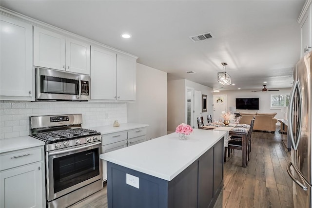 kitchen with visible vents, open floor plan, appliances with stainless steel finishes, tasteful backsplash, and wood-type flooring