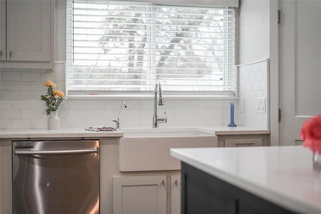 kitchen featuring tasteful backsplash, light countertops, a sink, and stainless steel dishwasher