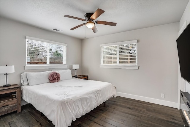 bedroom featuring visible vents, dark wood finished floors, a textured ceiling, and baseboards