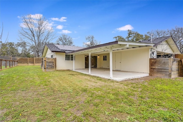 rear view of property with stucco siding, a fenced backyard, a lawn, and a patio