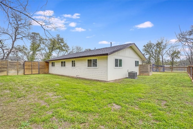 back of house with a fenced backyard, central AC unit, and a yard