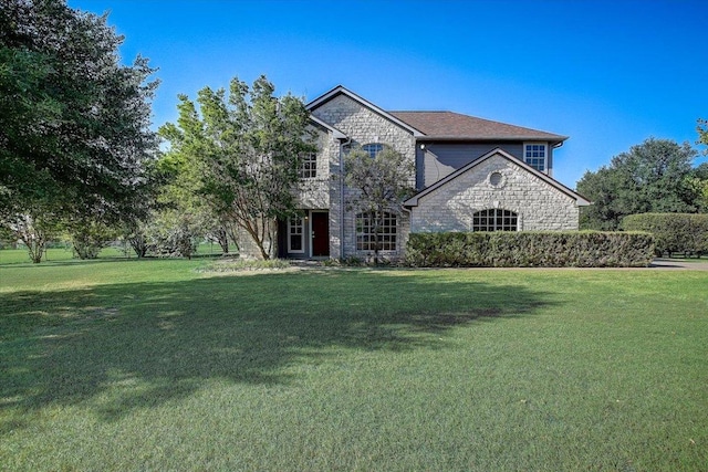 french provincial home with stone siding and a front lawn