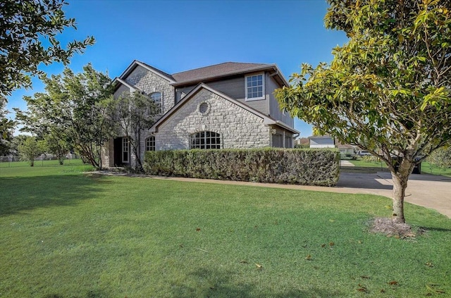 view of front of property with a garage, stone siding, driveway, and a front lawn