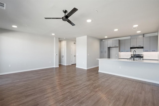 unfurnished living room with baseboards, a ceiling fan, dark wood-type flooring, a sink, and recessed lighting