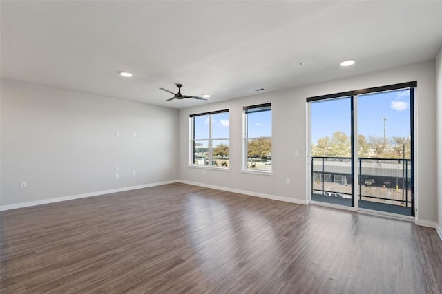 unfurnished room with a healthy amount of sunlight, dark wood-style floors, and baseboards