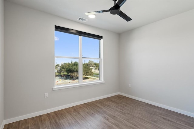 spare room featuring a ceiling fan, wood finished floors, visible vents, and baseboards