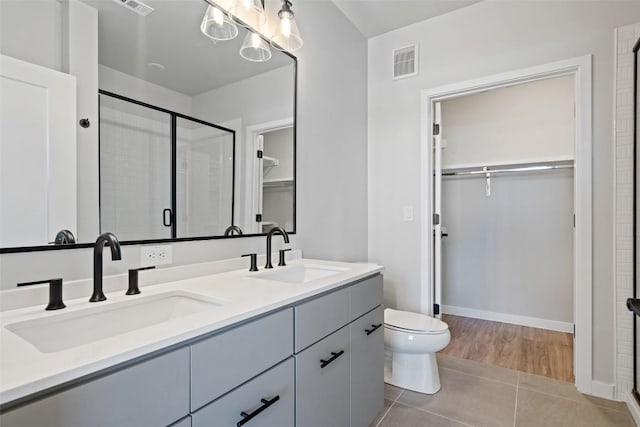 full bathroom featuring a walk in closet, visible vents, a sink, and a shower stall