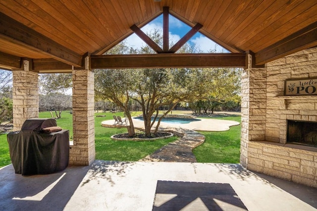 view of patio / terrace with an outdoor stone fireplace and area for grilling