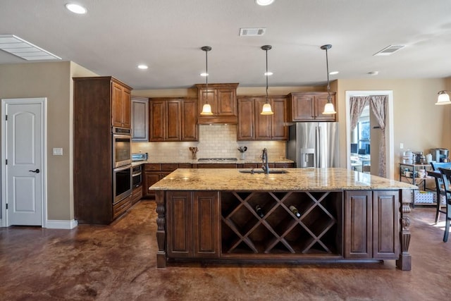 kitchen featuring visible vents, decorative backsplash, an island with sink, appliances with stainless steel finishes, and a sink