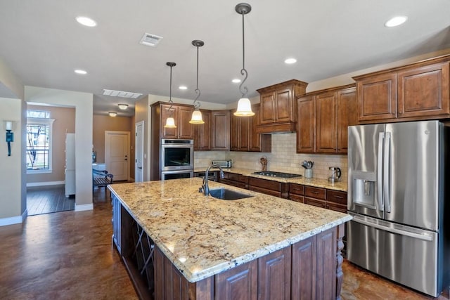 kitchen featuring a kitchen island with sink, a sink, visible vents, appliances with stainless steel finishes, and backsplash