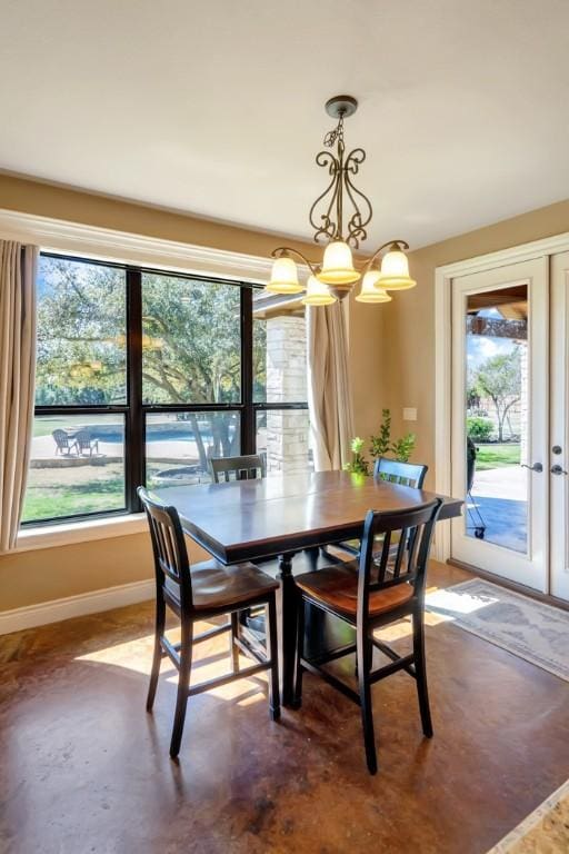 dining room featuring concrete floors, baseboards, a notable chandelier, and french doors