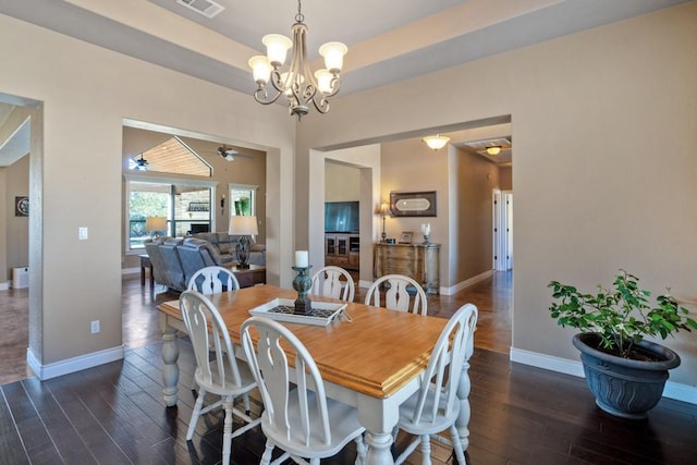 dining space with ceiling fan with notable chandelier, wood finished floors, visible vents, baseboards, and a tray ceiling