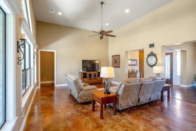 living room with recessed lighting, concrete floors, a towering ceiling, and baseboards