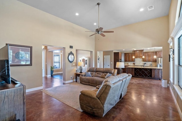 living room featuring finished concrete floors, visible vents, a towering ceiling, and baseboards